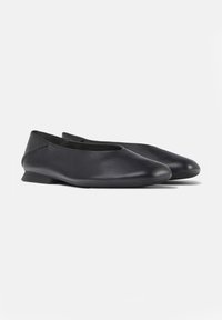 Ein Paar schwarze Lederballerinas mit niedrigen Absätzen und runden Zehen auf einem schlichten weißen Hintergrund.