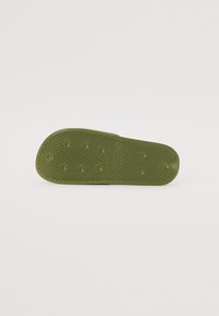 Grønn gummisåle med teksturert overflate med hevede prikker og et diamantmønster for grep. Ingen synlig merkevare eller aksenter.