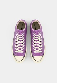 Purple canvas sneakers with white laces, rubber toe cap, and cream sole. Features metal eyelets and branded insoles.