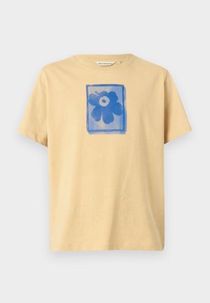 Tricou din bumbac de culoare bej deschis, cu un grafic floral albastru într-un cadru rectangular pe față. Mâneci scurte și guler rotund.