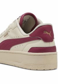 Puma CA Match sneakers feature a cream leather upper with burgundy accents, a flat white rubber sole, and a raised gold logo on the heel.