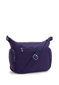 Borsa a tracolla di tessuto viola con una finitura testurizzata, tasche con zip sui lati e una tracolla regolabile. Non presenta loghi o fantasie visibili.