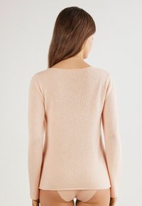 Langarm, hellrosa Pullover mit weicher Textur, rundem Ausschnitt und leicht lockerer Passform. Die Rückansicht zeigt eine glatte Oberfläche.