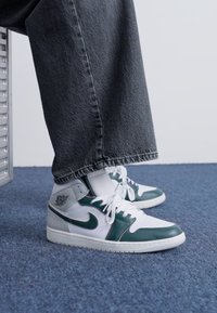 Sneakers înalte, alb și verde închis, cu un upper din piele, accente texturate și logo-ul clasic Nike Swoosh.