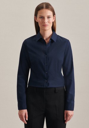 Marineblauwe overhem shirt met lange mouwen, klassieke kraag en een getailleerd ontwerp, gemaakt van gladde stof. Draagt met zwarte op maat gemaakte broek.