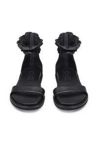 Sandali neri con materiale liscio, dotati di una larga fascia sul dito, una cinturino alla caviglia con dettagli arricciati e una suola piatta.