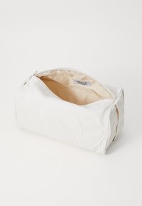 Neceser blanco con cremallera y un exterior suave, con un diseño de logo texturizado. El interior es beige y se puede ver una etiqueta dentro.