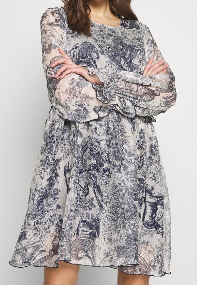 Průhledné šaty s vzorem a dlouhými rukávy, zdobené modro-krémovým zvířecím designem. A-liniový tvar s nařasenými manžetami a lemem.