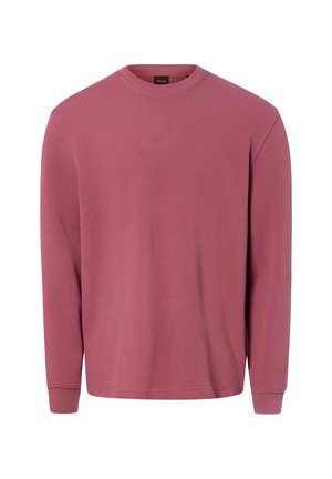 Langärmeliger, rundhalsiger Strickpullover in staubigem Rosé mit gerippten Bündchen und einem kleinen schwarz-orangenen Etikett innen am Kragen.
