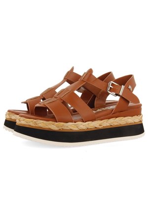 Brown faux leather sandals with wide straps, braided jute midsole, black platform, and adjustable ankle buckle.