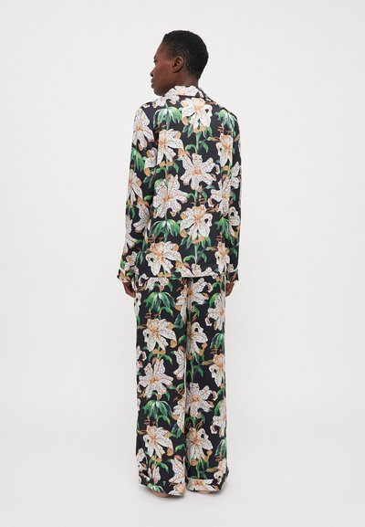 Floral pajama set featuring a black background, large white lilies, and green leaves. Long sleeves and wide-leg pants made from lightweight fabric.