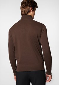 Brązowy sweter z dzianiny z wysokim kołnierzem, z prążkowanymi mankietami i dołem. Wykonany z miękkiego materiału, zaprojektowany z myślą o dopasowanej sylwetce.