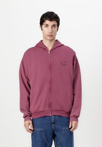Hanorac burgundy cu fermoar, dotat cu o buzunar frontal, manșete și tiv ribbate. Prezintă un mic logo imprimat în zona stângă a pieptului. Material moale, texturat.