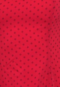 Κόκκινο ύφασμα με ομαλή υφή, με σκοτεινά κόκκινα πουά διατεταγμένα ομοιόμορφα. Το σχέδιο είναι συνεπές σε όλη την επιφάνεια.