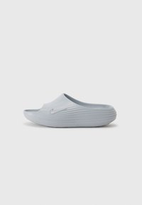 Nike sivi gumeni klompi s reljefnim dizajnom, otvorenim prstima i bez peta. Ima mali, utisnuti logo sa vanjske strane. Teksturirana obuća.