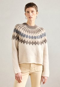 Πλεχτό κρεμ πουλόβερ με σχέδιο στρογγυλής λαιμόκοψη που περιλαμβάνει μπλε και καφέ μοτίβα, μακριά μανίκια και χαλ�αρή cropped εφαρμογή.