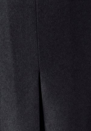 Detailný záber tmavosivej látky s vertikálnym švom a malým rázvorom uprostred.