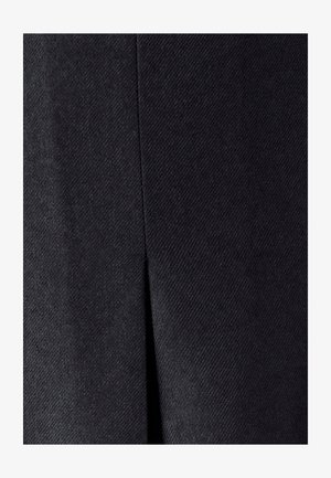 Primo piano di tessuto grigio scuro con una cucitura verticale e un piccolo spacco al centro.