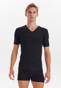 Black V-neck t-shirt with short sleeves. Soft, stretchy fabric. Casual fit, smooth texture, paired with black fitted shorts.