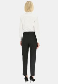 Czarne spodnie o dopasowanym kroju z subtelnym wzorem, o prostym kroju i średnim stanie, zestawione z białą koszulą z kołnierzykiem i czarnymi szpilkami.