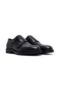 Black leather shoes with a smooth finish, featuring a double buckle design, rounded toe, and a rugged rubber sole.