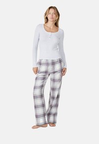 Grijze lange mouwen top met een ronde halslijn en knoopdetails, gecombineerd met geruite pyjamabroek in lavendel-, wit- en blauwtinten.