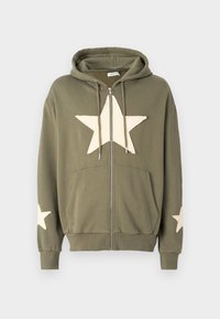 Felpa con zip di colore verde oliva, realizzata in cotone, con una grande stella crema sul davanti e stelle più piccole su entrambe le maniche. Include tasche frontali.