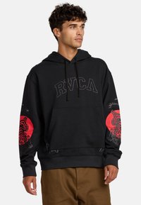 Schwarzer Hoodie mit Kängurutasche und Kordelzugkapuze, verziert mit roten Grafiken eines Tigers auf den Ärmeln und einem Logo auf der Brust.