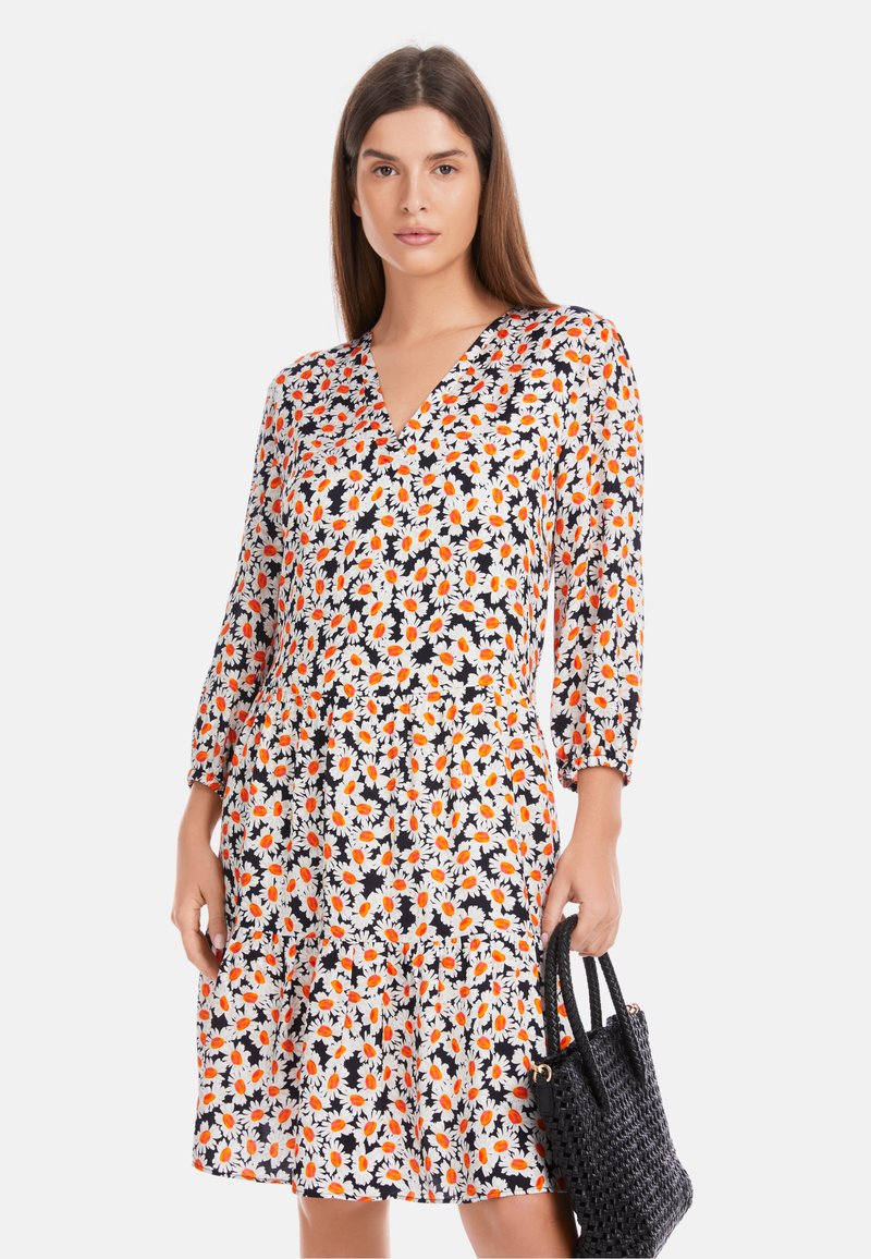 Floral dress with a V-neck, 3/4 sleeves, featuring a black background with orange and white daisies; soft fabric, relaxed fit, tiered at the hem.