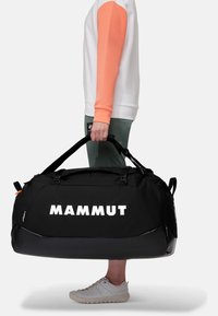 Fekete sporttáska "MAMMUT" logóval, strapabíró fogantyúkkal és állítható pántokkal. Az anyag textúrált felülettel rendelkezik; kiegészítők narancssárga fém alkatrészek.