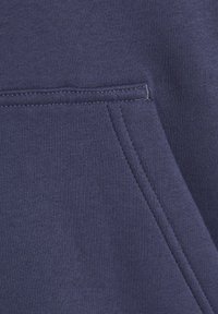 Navyblauer Stoff mit glatter Textur, ausgestattet mit einer aufgesetzten Tasche und kontrastierenden Nahtdetails. Das Material erscheint weich und bequem.