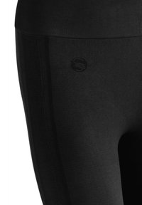Leggings neri realizzati in un materiale morbido e elasticizzato con vita a coste, caratterizzati da un logo sottile e una texture liscia.