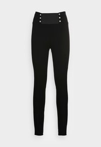 Leggings negros con una cintura alta que presentan cuatro adornos de botones plateados. Textura suave y diseño ajustado que se estrecha hacia el tobillo.