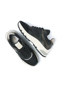 Pair of black and white sneakers with textured gold accents, thick white soles, mesh and leather uppers, and black laces on a white background.
