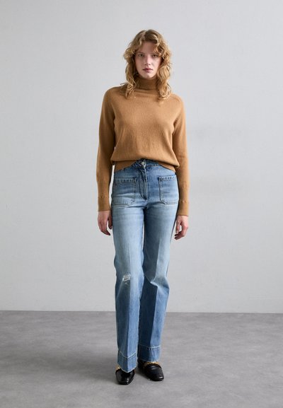 Barna garbó, világoskék trapéz farmer, kopott részletekkel, és fekete cipő. Egyszerű design, puha textúra és laza szabás.