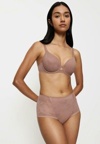 Hnědá krajková podprsenka s květinovým vzorem a hladkým povrchem, doplněná o odpovídající vysoké kalhotky. Oba kusy mají jemný lesk a elegantní design.