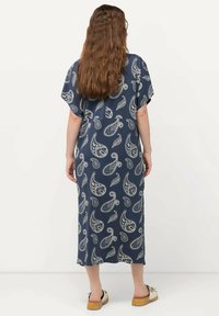 Laivastonsininen maksi mekko, jossa on paisley-kuvio. Lyhyet hihat, rento malli ja kevyttä kangasta. Saatavana litteiden, avoimien kenkien kanssa.