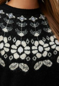 Czarny sweter dzianinowy z białymi wzorami kwiatowymi i akcentami geometrycznymi. Okrągły dekolt z miękkim, teksturowanym wykończeniem.