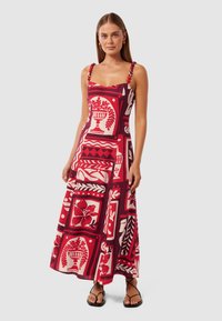 Maxi-jurk in rood en wit met decoratieve bloemen- en urnpatronen. Voorzien van schouderbanden versierd met pompons en een ontspannen pasvorm.