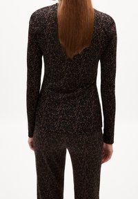 Langärmliges Oberteil und Hose in Schwarz mit braunem Blumenmuster. Weicher Stoff, enganliegendes Design, runder Ausschnitt und glatte Textur.