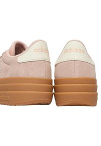 Paire de baskets Adidas rose clair avec des languettes de talon beige et des semelles en caoutchouc marron épaisses vues de dos.