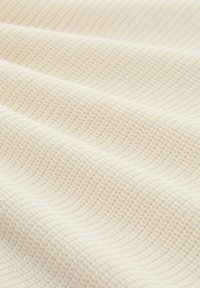 Getextureerde crème stof met een verhoogd, golvend patroon, die een zachte, geweven uitstraling heeft. Het materiaal heeft een subtiele glans en een uniforme kleur.