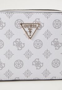 White textured material wallet with grey logo pattern, triangular metal logo accent, and a zip closure.