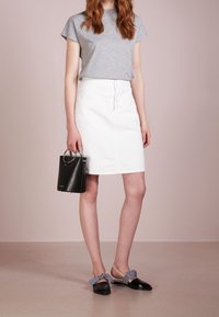 Gray short-sleeve t-shirt, white denim skirt, black handbag with circular handle, and black loafers with gingham accents.