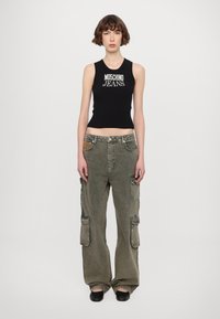 Schwarzes, geripptes Tanktop mit dem Aufdruck "Moschino Jeans", kombiniert mit hellolivenfarbenen Cargo-Hosen, die mehrere Taschen und eine lockere Passform aufweisen.