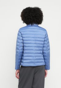 Hele sinine puffer-mantel vertikaalsete tepitud detailidega, kõrge krae ja pikkade varrukatega. Sile, läikiv materjal ja vormikas lõige.