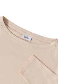 Beige long-sleeve shirt with a round neckline and a "CECIL" brand label sewn inside the collar.