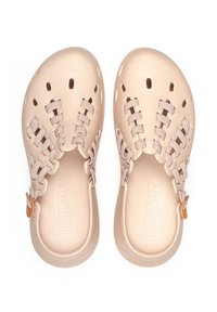 Zuecos de color beige claro con un diseño perforado, cordones de textil y suelas de goma. Presentan un pequeño acento naranja cerca del talón y detalles del logo.