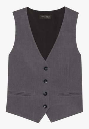 Gilet gris avec un design en V, comportant six boutons, deux poches latérales et une texture lisse. L'étiquette indique "ANNA FIELD."
