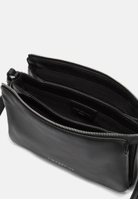 Borsa in pelle nera con chiusura a zip, dotata di più scomparti interni. Texture liscia con un dettaglio del logo sul davanti.